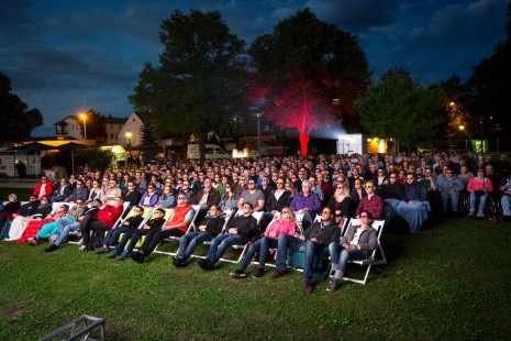 Blick auf das Publikum, das bei einem Open Air-Kino auf die Leinwand schaut.