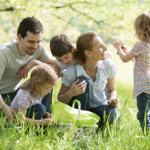 Eine Familie mit drei Kindern beim Spielen auf einer Wiese