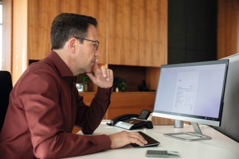Schmuckbild, das einen Mann zeigt, der vor einem Computerbildschirm sitzt und liest.